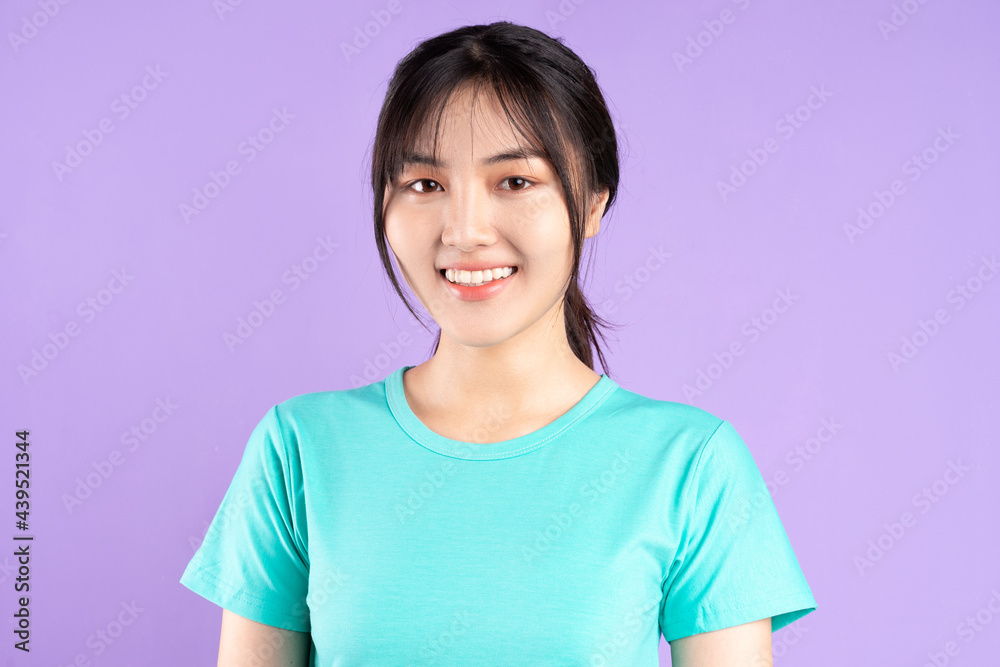 Young asian girl in cyan shirt using phone on purple background Young asian girl in cyan shirt using phone on purple background