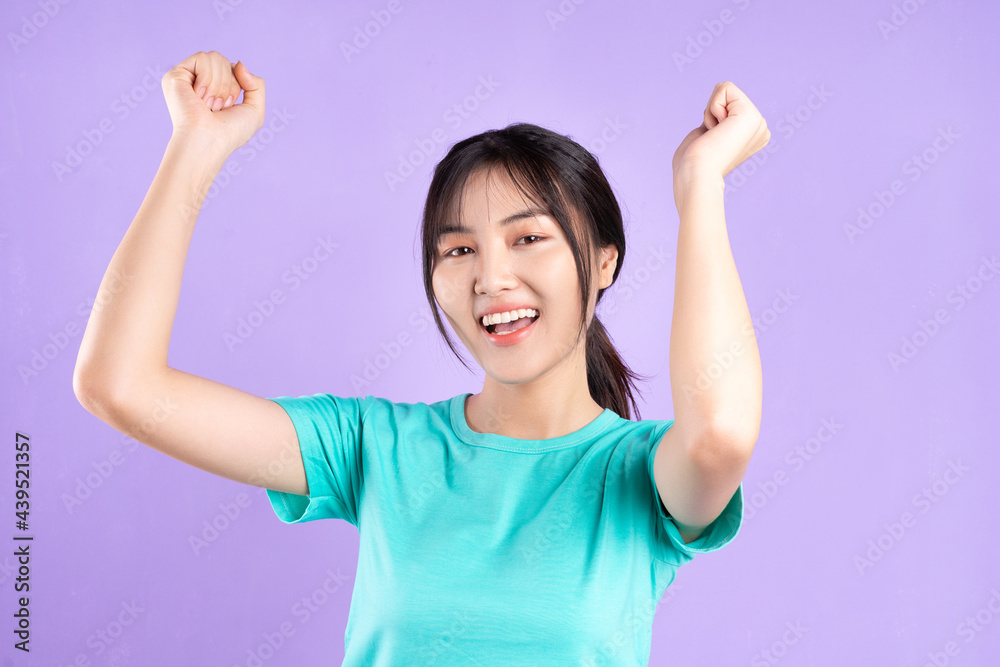 Young asian girl in cyan shirt using phone on purple background