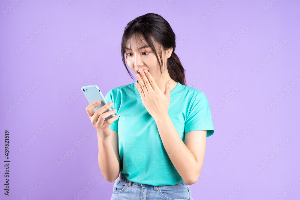 Young asian girl in cyan shirt using phone on purple background Young asian girl in cyan shirt using phone on purple background