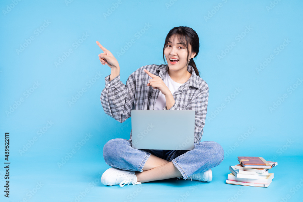 Asian female student with playful expression on blue background Asian female student with playful expression on blue background