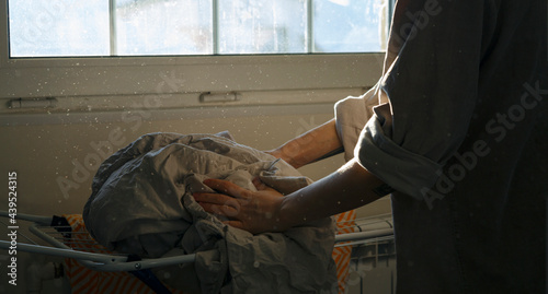 Crop woman putting sheet on drying rack