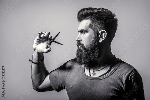 Bearded man isolated on gray background. Mans haircut in barber shop. Barber scissors, barber shop. Barber scissors. Vintage barbershop, shaving. Black and white