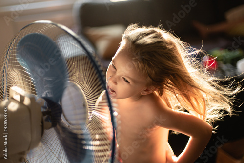 Toddler girl playing in front of the fan photo