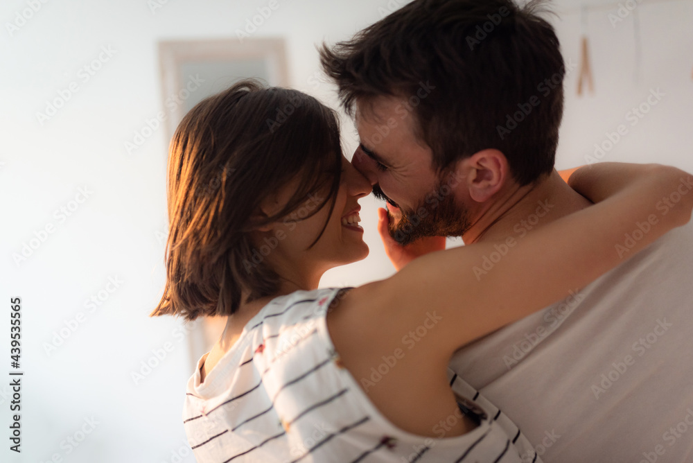 Young couple kissing and cuddling while siting on the bed. Young couple kissing and cuddling while siting on the bed.