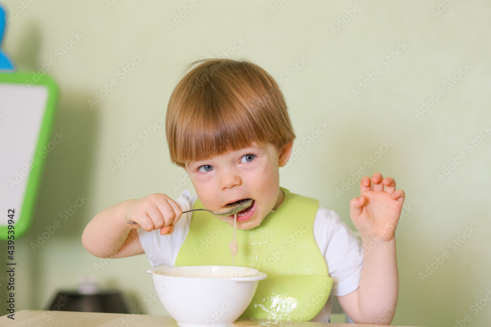 Happy cute infant baby boy spoon eats itself Happy cute infant baby boy spoon eats itself