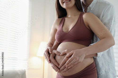 Pregnant young woman making heart with hands on belly and husband near her at home, closeup. Space for text Free Download Pregnant young woman making heart with hands on belly and husband near her at home, closeup. Space for text - GFXLoad