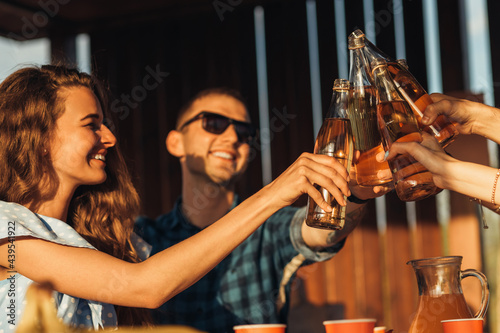 Photography Young friends celebrate at sunset dinner, toast with drinks, happy people at ter