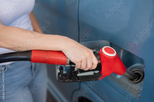 Caucasian woman refueling a car at a self-service gas station.