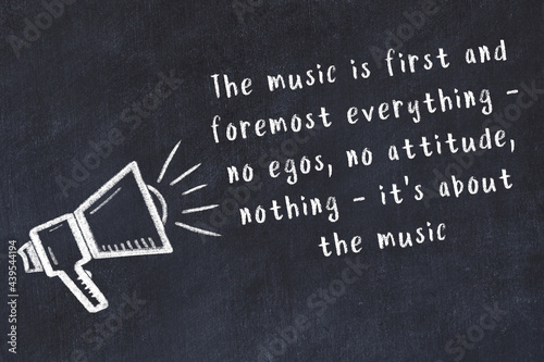 Chalk sketch of loudspeaker on black desk and movitational quote