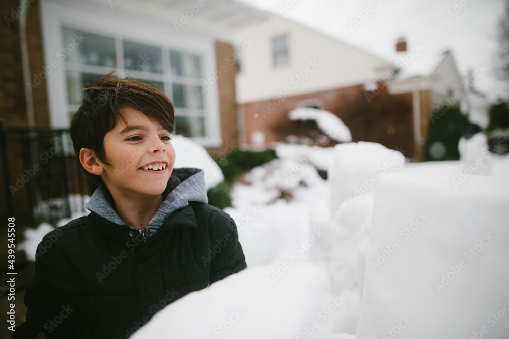 © Maria Manco/Stocksy - boy hides behind snow fort for snowball fight