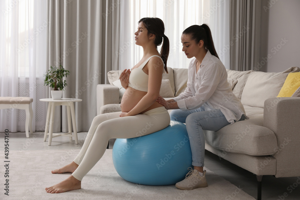 Doula working with pregnant woman in living room. Preparation for child birth Doula working with pregnant woman in living room. Preparation for child birth