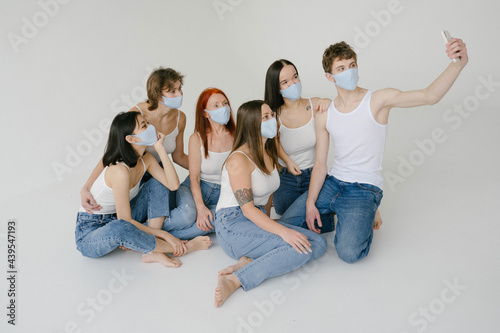 Group of diverse people in masks taking selfie in studio photo