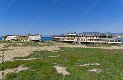 An old abandoned river boat stands on the ground near the sea. photo