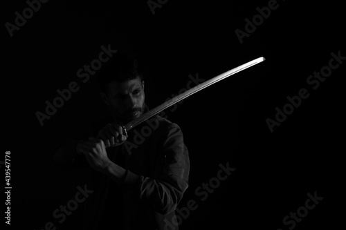 Fighter with katana sword in shadows in black and white