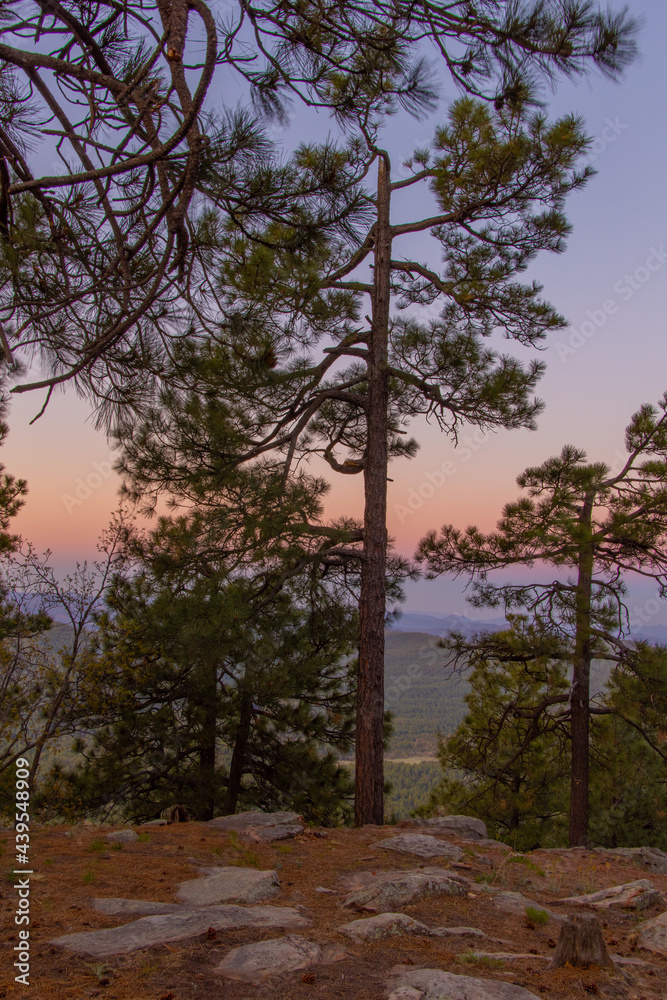 In Payson, Arizona this is known as the Mogollon Rim. The sun sets looking out over the rim, through the trees, the colorful sky paints the ledge and flowing hills, boulders and trees colorful shades 