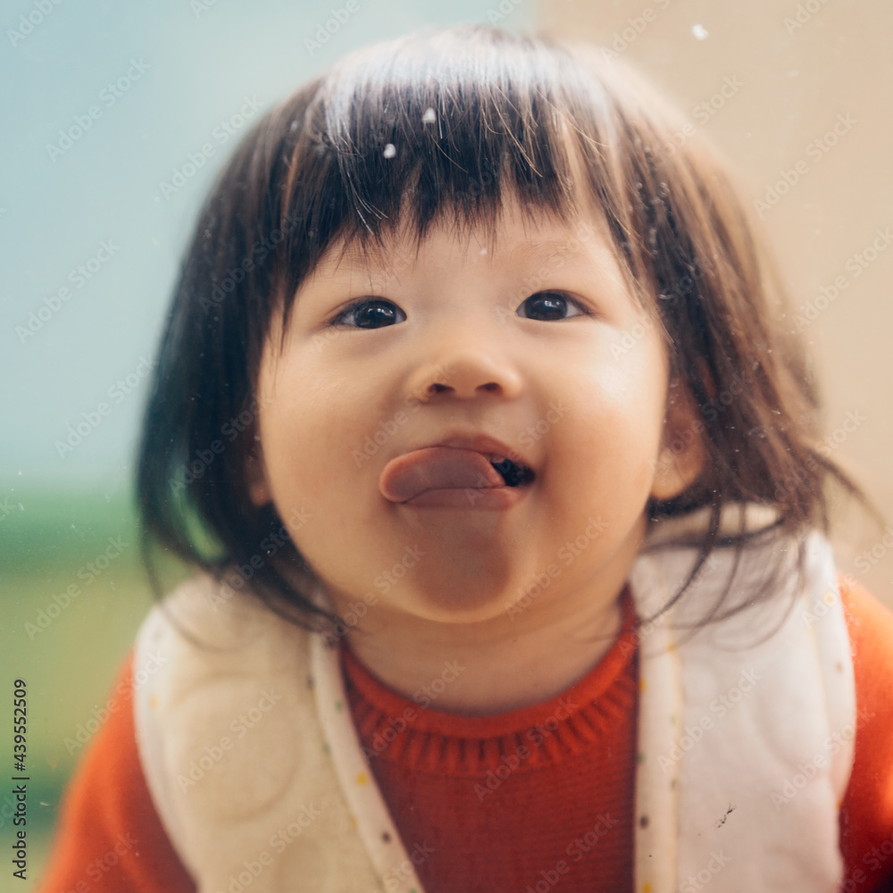 Portrait of cute little girl behind glass