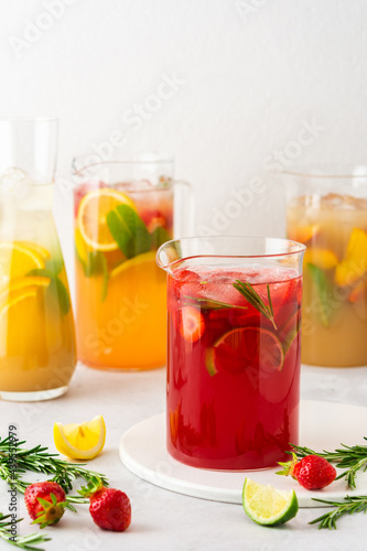 Jugs of fresh refreshing fruit drinks with fruit wedges, summer cold juices with ice © pundapanda