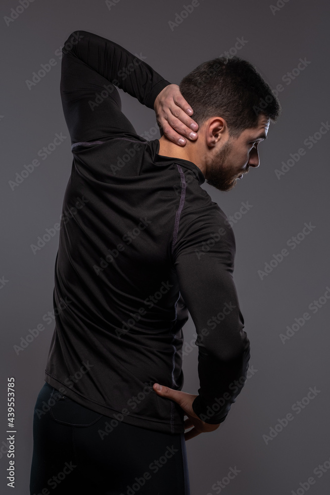 Rear view of athletic man stretching on grey background