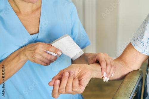 Ärztin misst Fieber am Handgelenk einer Seniorin mit Infrarot