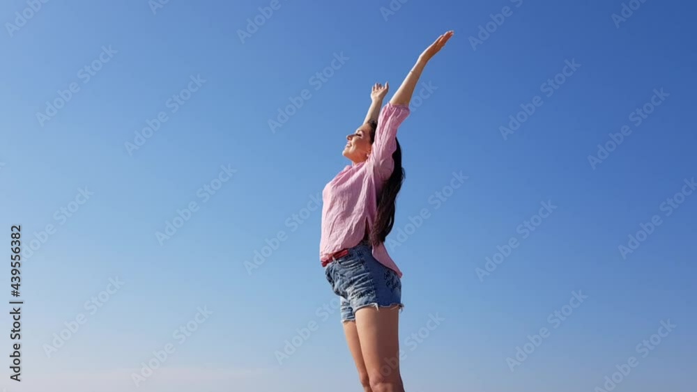 Beautiful Young Woman with Arms Wide Open to Celebrate Her Success. Warm Weather with Sun and Sky is Blue. Beautiful Young Woman with Arms Wide Open to Celebrate Her Success. Warm Weather with Sun and Sky is Blue.