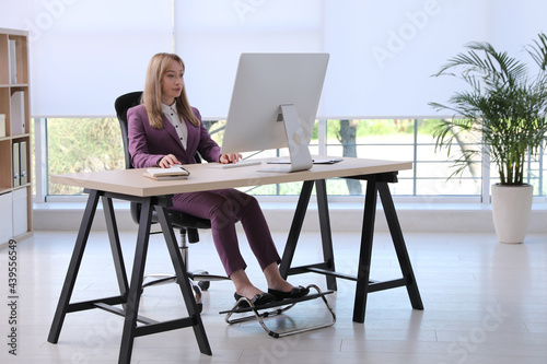 Woman using footrest while working on computer in office