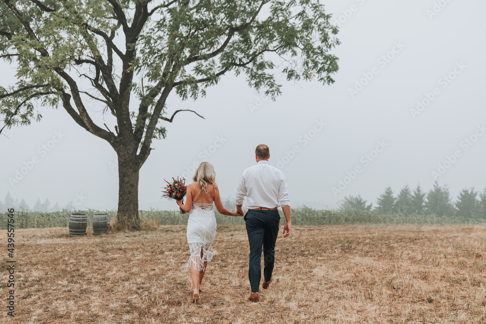 Bride and Groom Walking under Tree in Field Bride and Groom Walking under Tree in Field