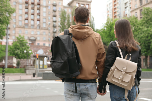 Young couple waiting to cross street, back view. Traffic rules and regulations