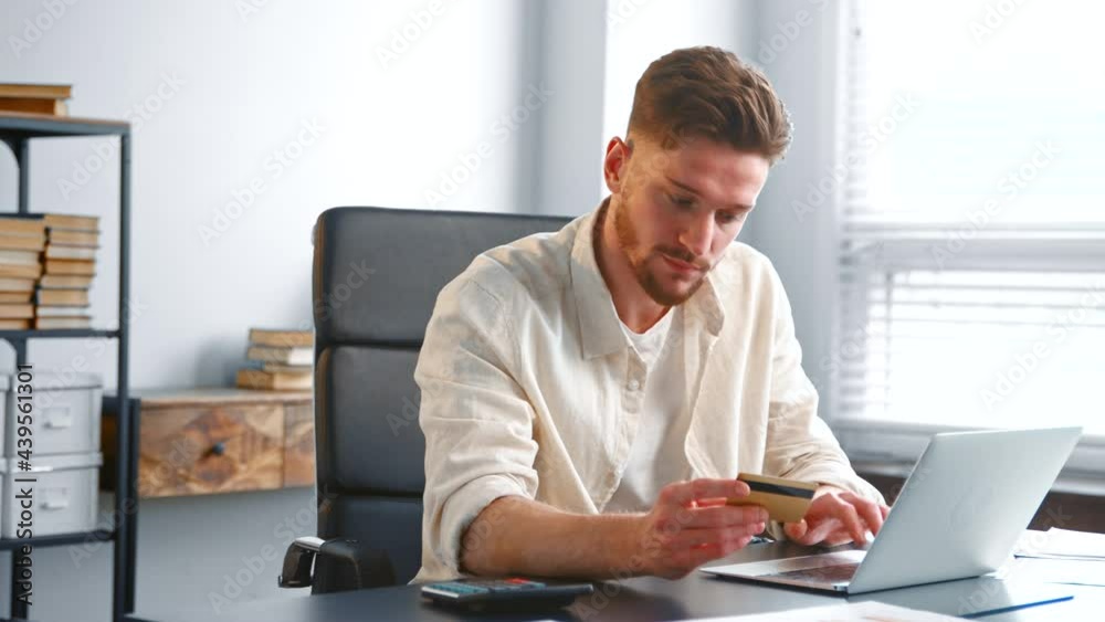 Bearded businessman in yellow shirt enters bank card info Bearded businessman in yellow shirt enters bank card info