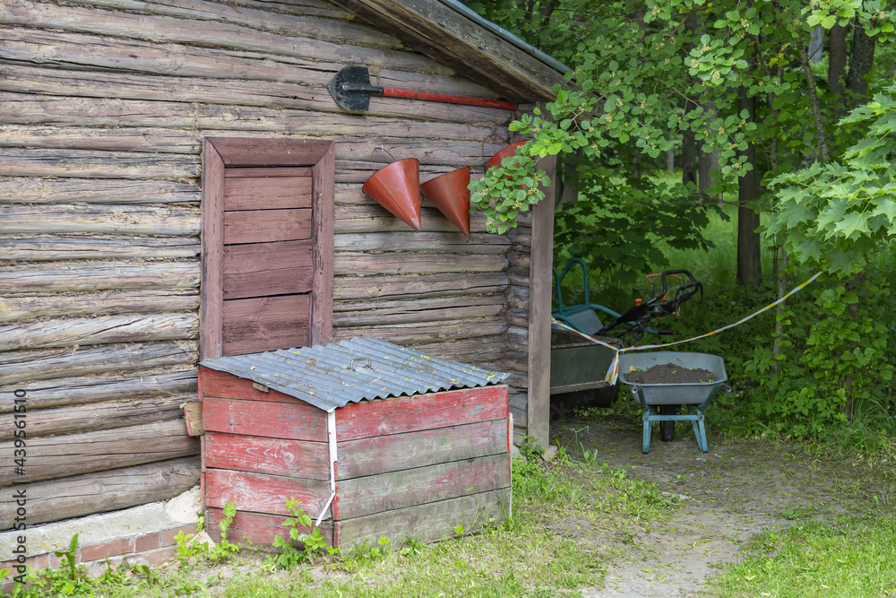 Wooden box with sand, old fire-fighting tools and garden equipment against the wall of a small country house Wooden box with sand, old fire-fighting tools and garden equipment against the wall of a small country house
