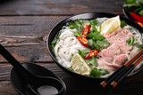 Pho Bo vietnamese soup with beef and noodles on a wooden background, selective focus