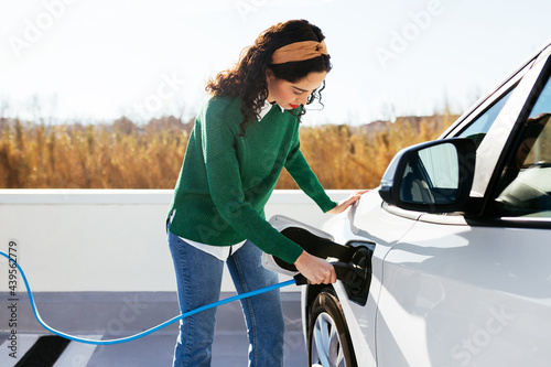 Young woman on electric car charge station