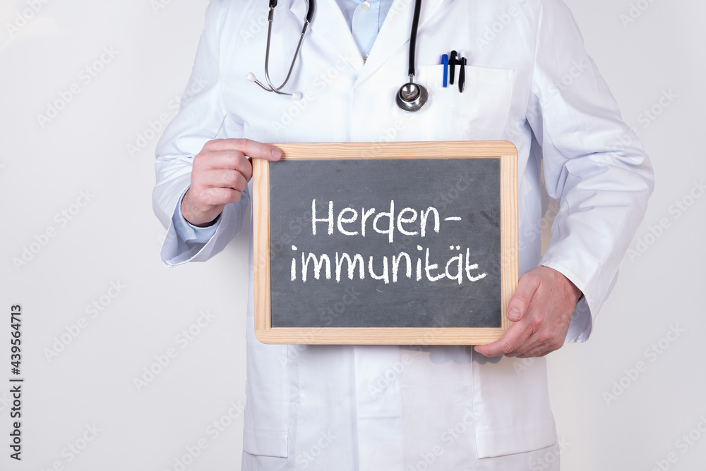 Arzt mit einer Tafel auf der Herdenimmunität in er Pandemie steht Arzt mit einer Tafel auf der Herdenimmunität in er Pandemie steht