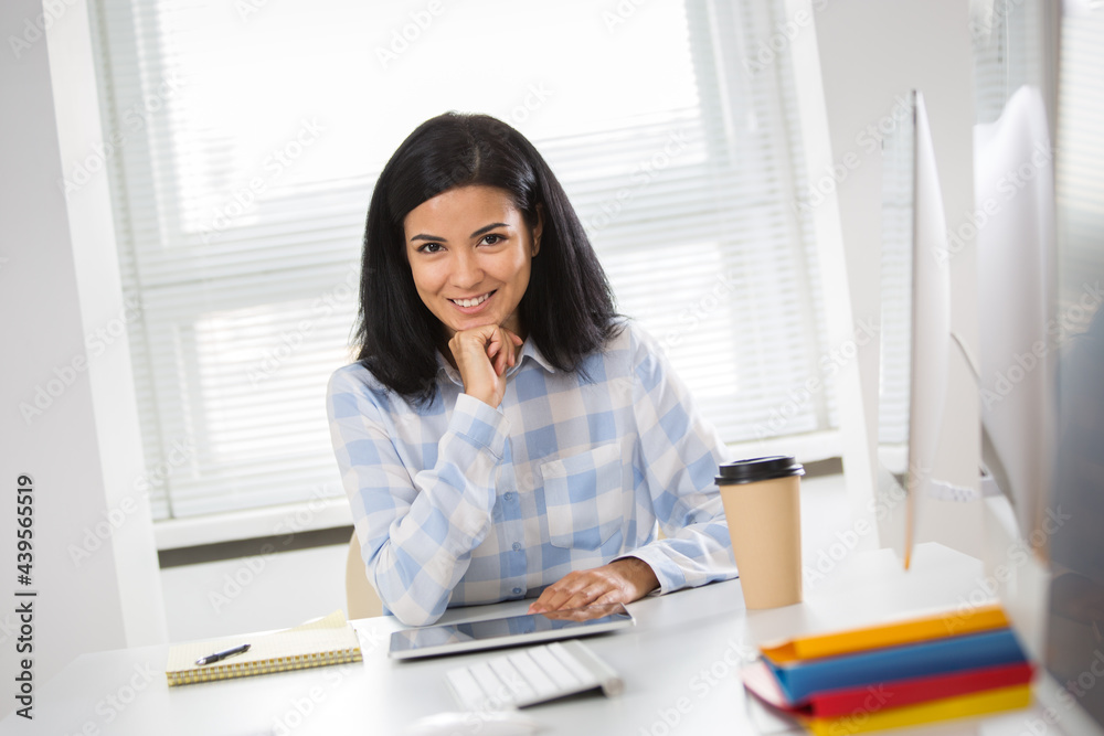 Portrait of hispanic business woman looking at camera at workplace in an office Portrait of hispanic business woman looking at camera at workplace in an office