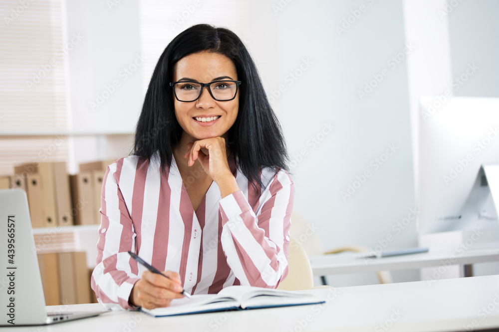 Portrait of hispanic business woman looking at camera at workplace in an office