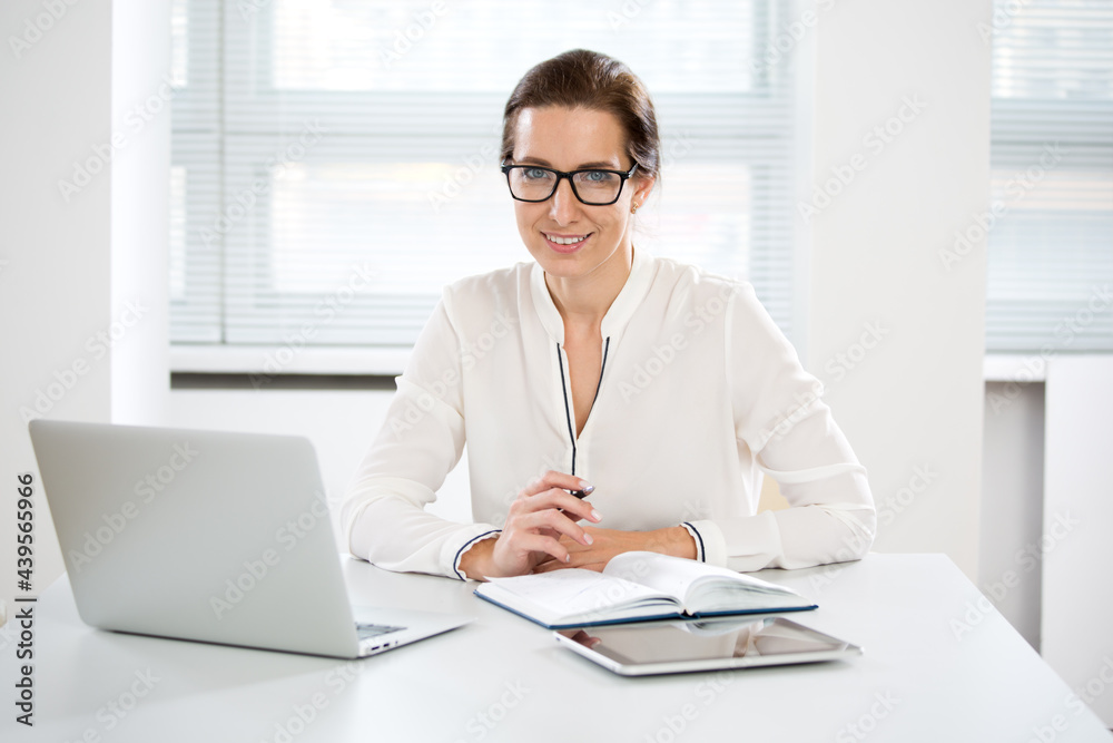 Portrait of business woman looking at camera at workplace in an office