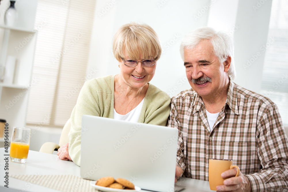 Elderly couple talking using laptop having breakfast together Elderly couple talking using laptop having breakfast together