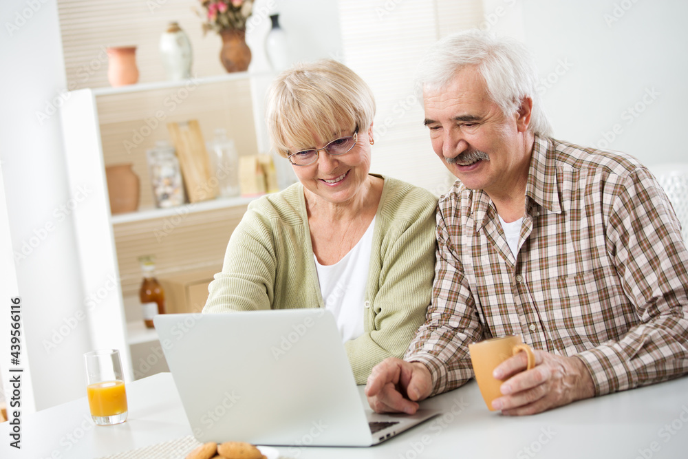 Elderly couple talking using laptop having breakfast together Elderly couple talking using laptop having breakfast together