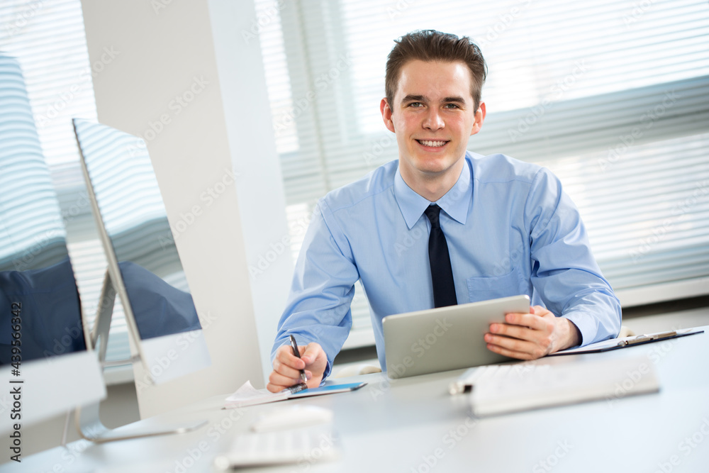 Portrait of young businessman working with laptop at office Portrait of young businessman working with laptop at office