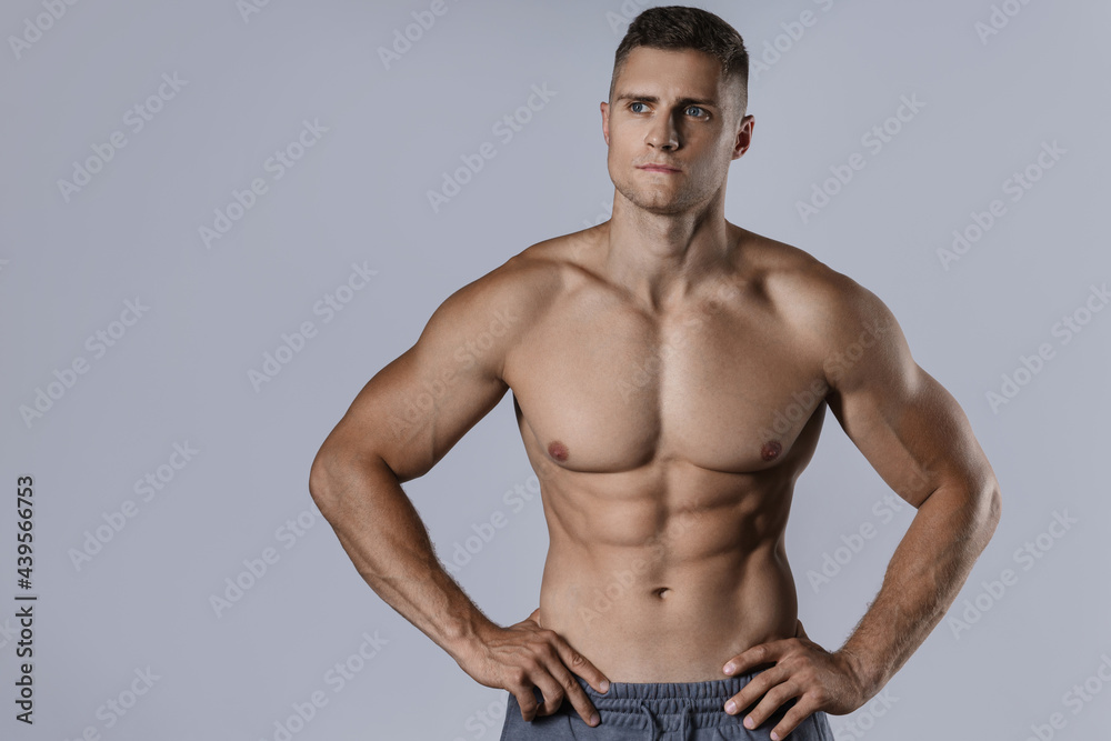 Bodybuilder showing his muscular body against gray background