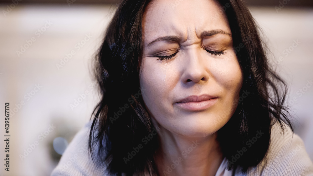 portrait of crying brunette woman with closed eyes on beige background portrait of crying brunette woman with closed eyes on beige background