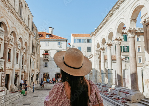 Rear view of young female tourist admiring the Peristyle in Diocletian's palace in Split, Croatia.