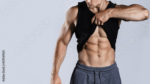 Foto Bodybuilder showing his abdominal muscles against gray background