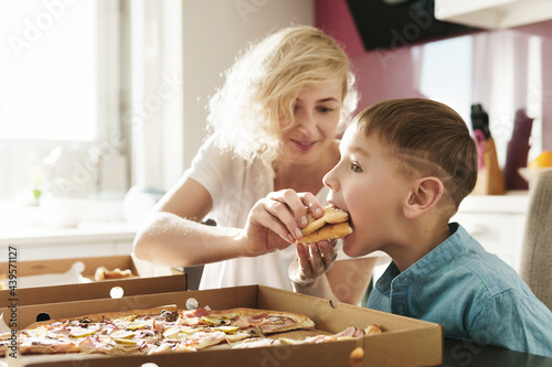 Mother and her cute son eating delicious pizza at home