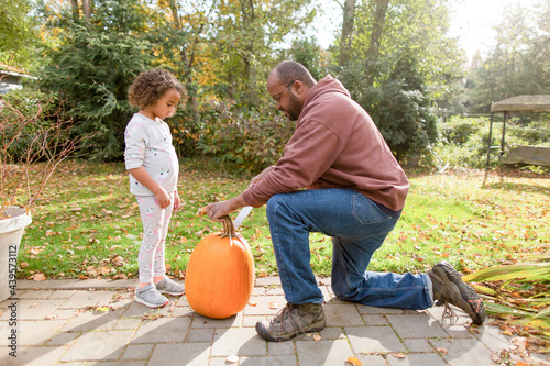 Black dad carves pumpkin with daughter photo