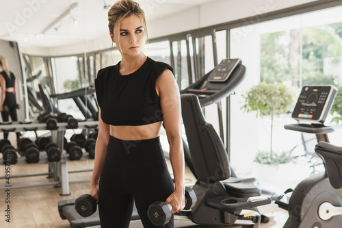 Athletic woman exercising with a dumbbells in the gym