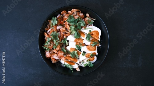 Salt egg spicy salad with dried shrimps on black background, Thai food breakfast.