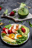 Ketogenic low carbs diet concept, Fried egg, avocado, strawberry, grilled chicken fillet, cheese, nuts and arugula. Detox smoothie, fresh green, Healthy food concept, top view