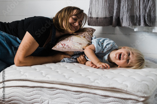 pregnant mother and daughter play on mattress photo
