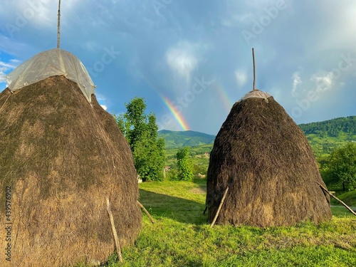 Rainbow over picturesque scene with hills and haystacks in Romania