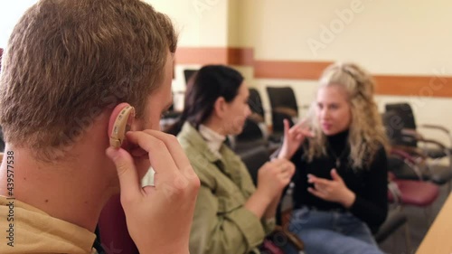 Three hard of hearing and deaf students communicate in sign language in a university classroom.